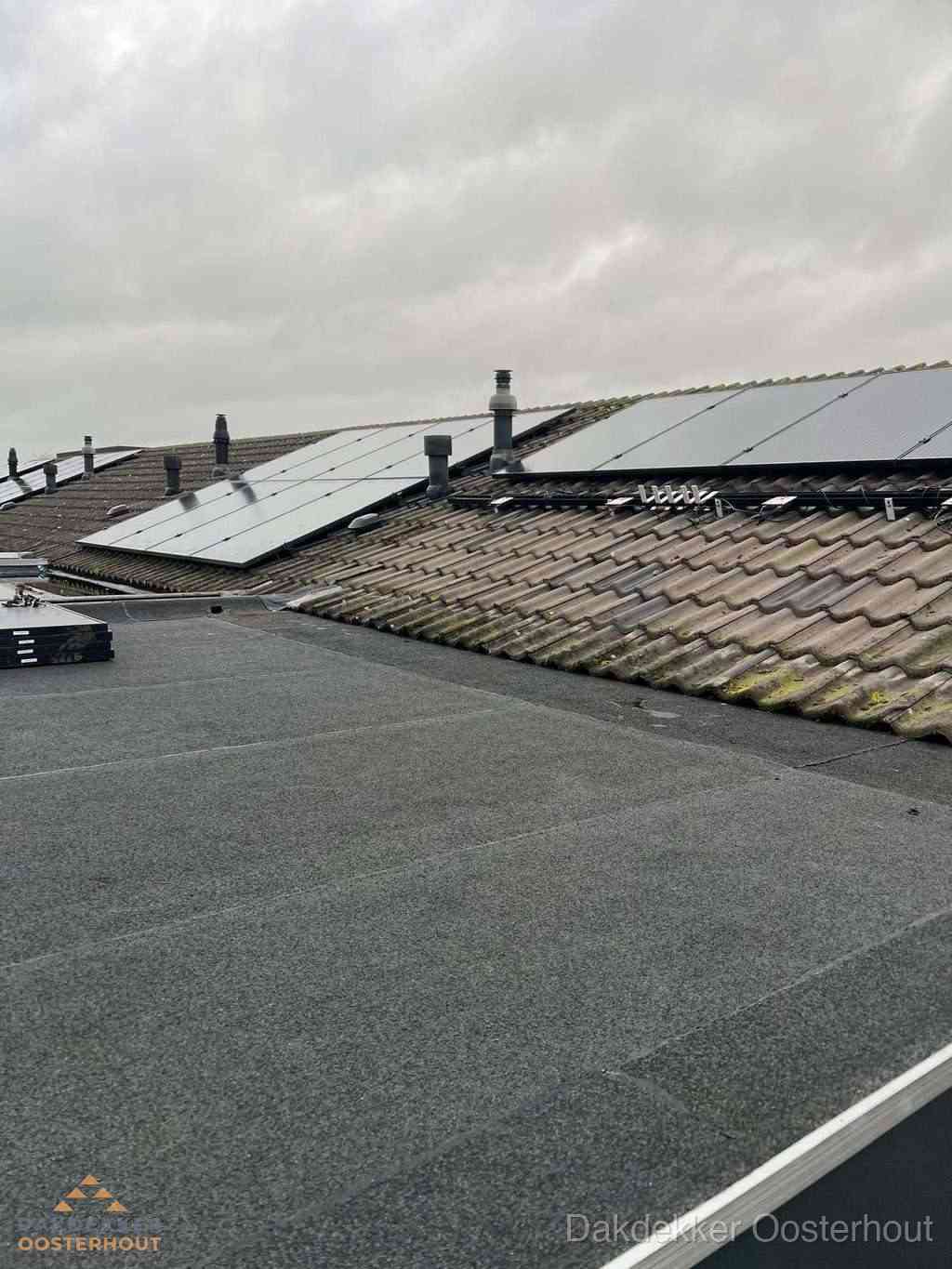 Plat dak inspectie met bitumen bedekking naast schuin pannendak in Oosterhout