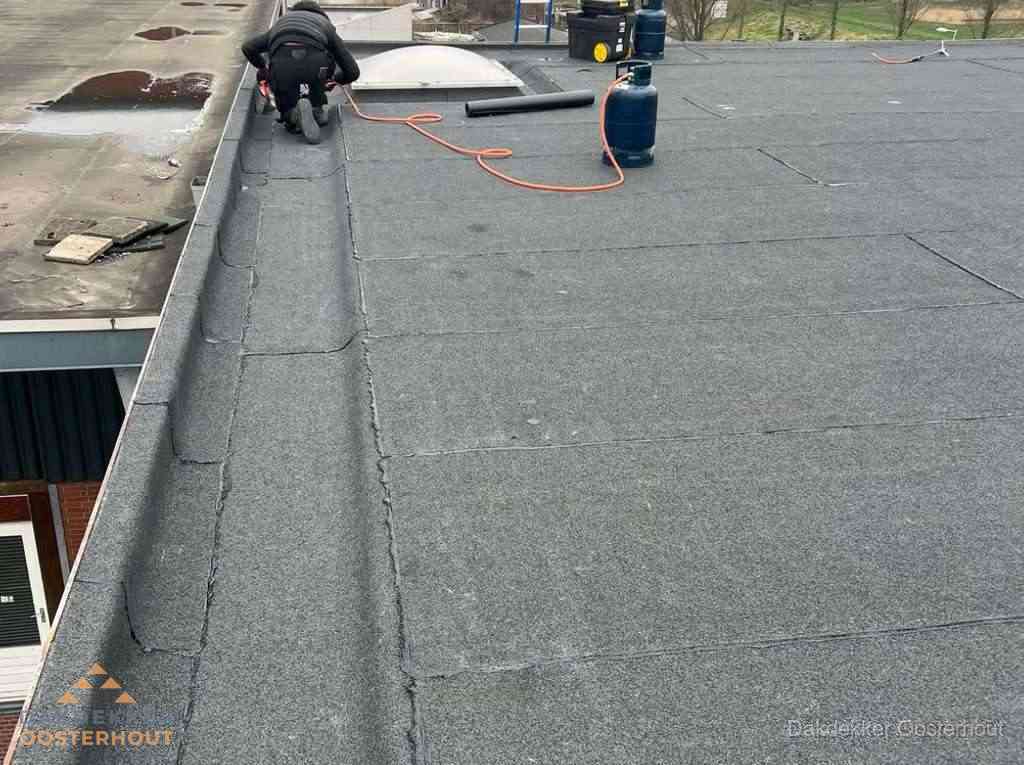 Dakdekker repareert bitumen dakbedekking op groot plat dak in Oosterhout